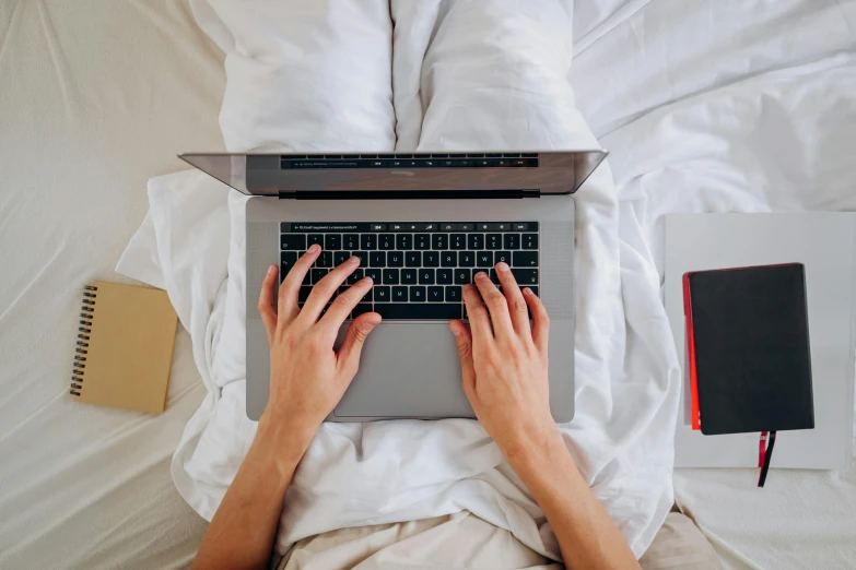 a person using a laptop on a bed, by Carey Morris, pexels, flat lay, multiple stories, covered, highly technical