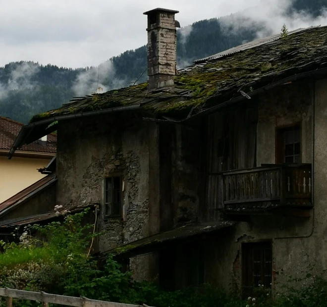 a couple of houses sitting on top of a lush green hillside, an album cover, inspired by Peter Zumthor, pexels contest winner, renaissance, rustic and weathered, chamonix, spooky photo, background image