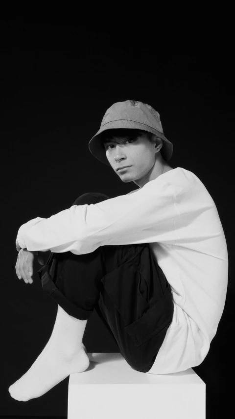 a man sitting on top of a white box, an album cover, inspired by Huang Gongwang, unsplash, realism, baggy clothing and hat, portrait black and white, headshot profile picture, portrait of a japanese teen