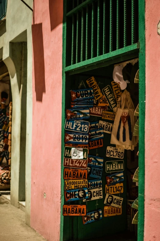 a street filled with lots of signs next to a building, by Emanuel Witz, cuba, colorful clothing, upclose, square