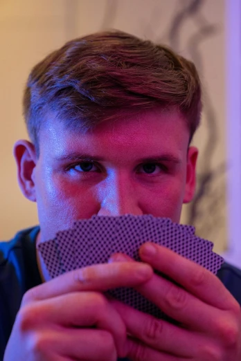 a close up of a person holding a card in front of their face, by Jacob Toorenvliet, tournament, discord profile picture, 18 years old, profile image