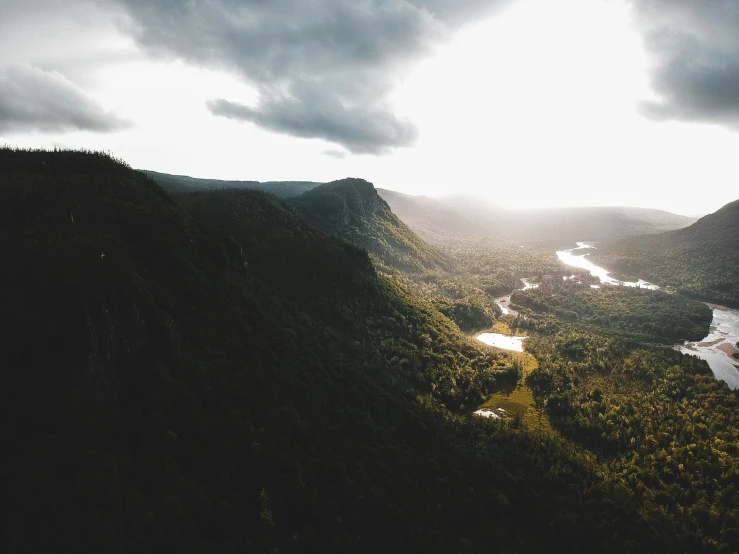 a river running through a lush green valley, by Jesper Knudsen, pexels contest winner, australian tonalism, ultrawide angle cinematic view, cliff side at dusk, soaring over a lake in forest, ominous! landscape of north bend