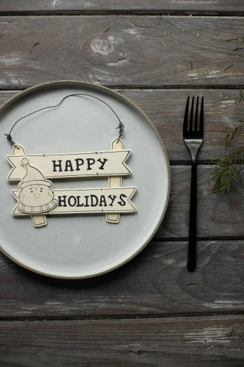 a plate with a sign that says happy holidays, by Haukur Halldórsson, organic ornament, fork, 4l, wooden