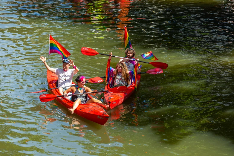 a group of people riding on top of a red boat, rainbows, las pozas, pride month, lourmarin