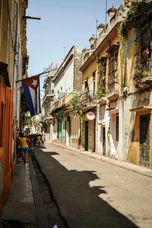 a man riding a bike down a street next to tall buildings, renaissance, cuban setting, shady alleys, a quaint, children's