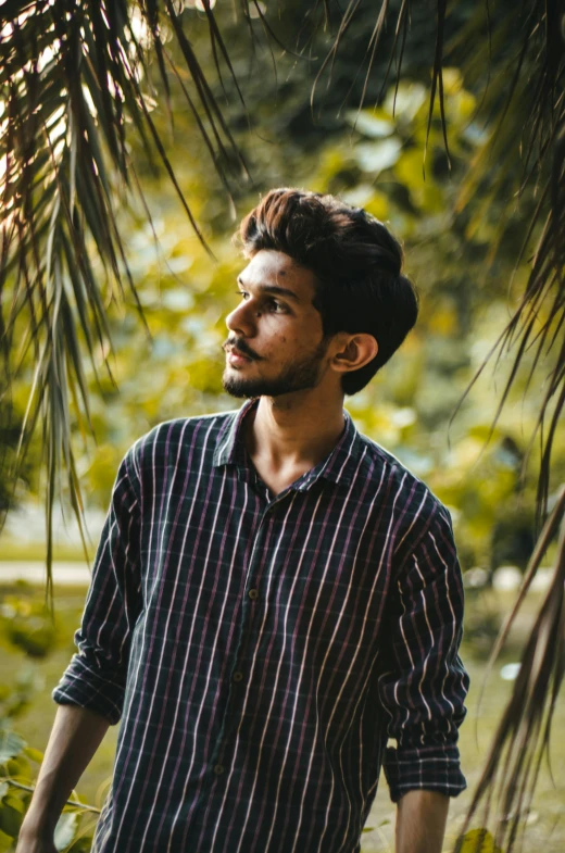 a man standing in front of a palm tree, by Max Dauthendey, pexels contest winner, wearing stripe shirt, profile pic, he is about 20 years old | short, long neck