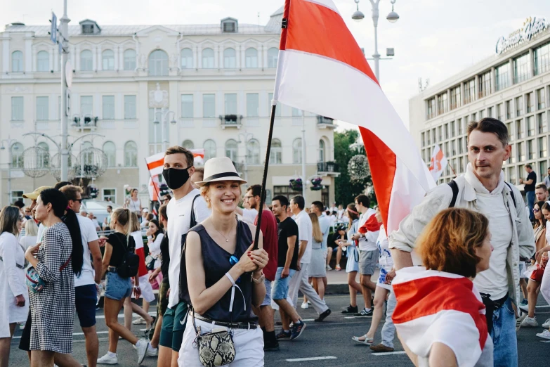 a group of people walking down a street holding flags, by Julia Pishtar, shutterstock, socialist realism, red and white, gen z, hrushevka on background, instagram post