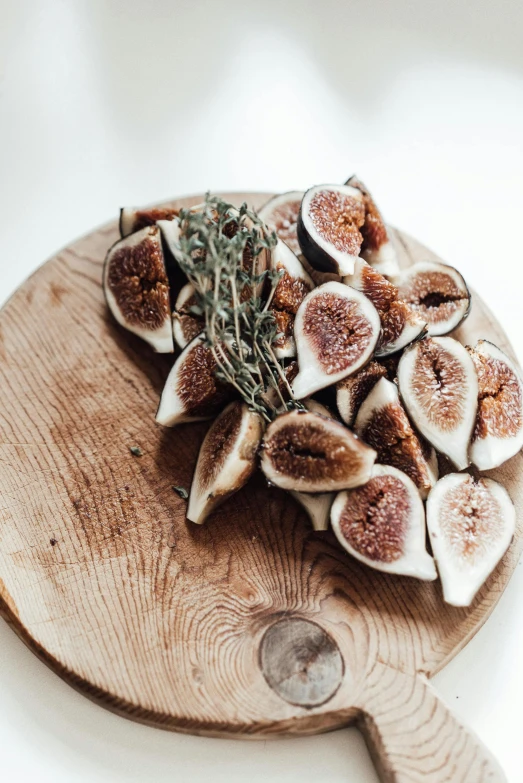 a cutting board with a bunch of figs on it, by Andries Stock, pexels contest winner, renaissance, made of glazed, herbs, natural wood top, unique design