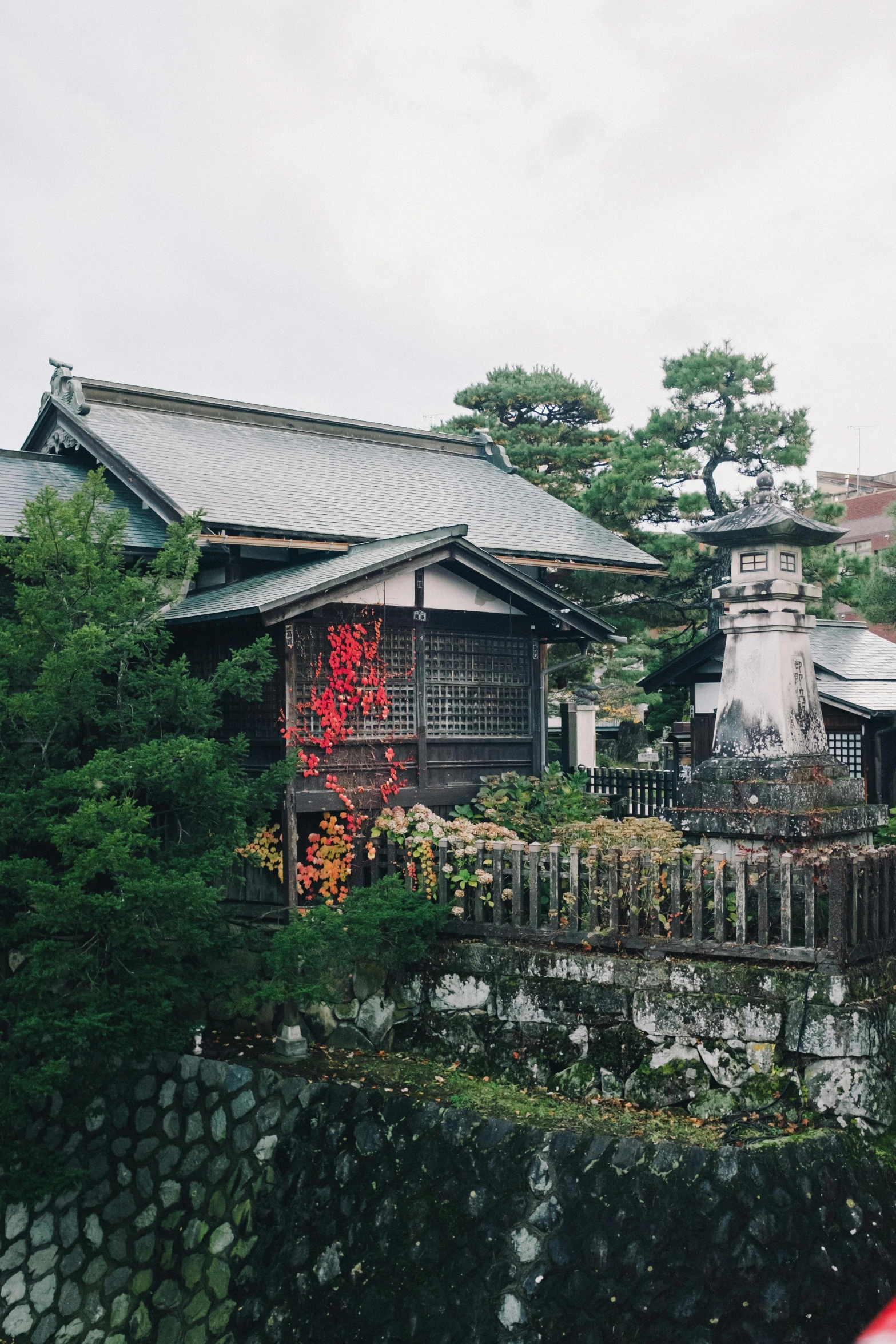 a red umbrella sitting on top of a lush green field, sōsaku hanga, chimneys on buildings, lush plants and lanterns, color image, onsen