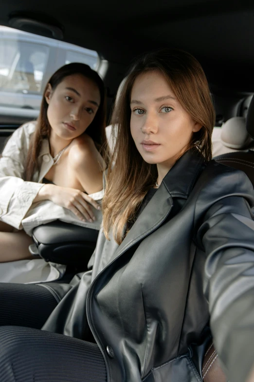 two women sitting in the back seat of a car, trending on pexels, photorealism, leather robes, kiko mizuhara, portrait sophie mudd, photoshoot for skincare brand