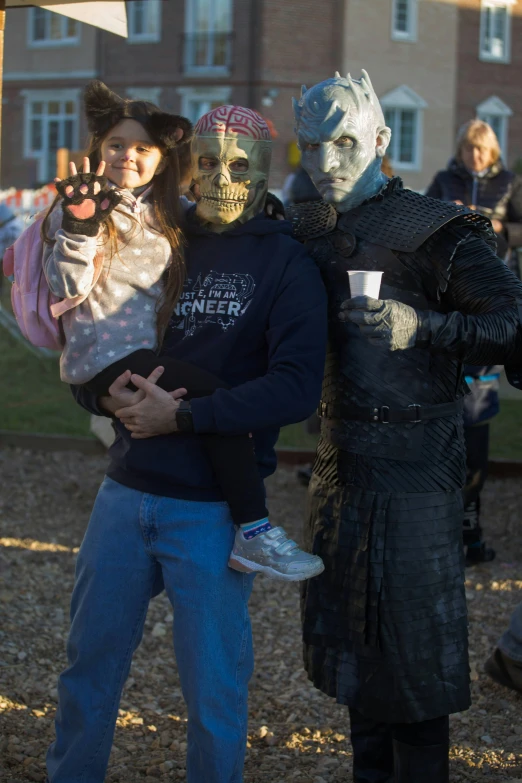 a couple of people standing next to each other, a photo, reddit, happening, frozen zombie man with a crown, with a kid, dressed in black body armour, 8k 50mm iso 10