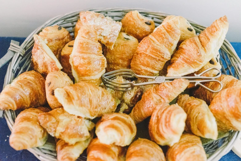 a basket full of croissants sitting on a table, unsplash, fan favorite, overflowing feast buffet table, 90s photo, very sunny