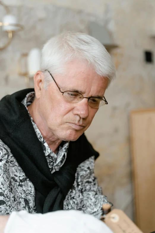 a man sitting in front of a laptop computer, a photorealistic painting, inspired by Károly Markó the Elder, trending on unsplash, photorealism, silver haired, professional woodcarving, looking serious, wearing cross on robe