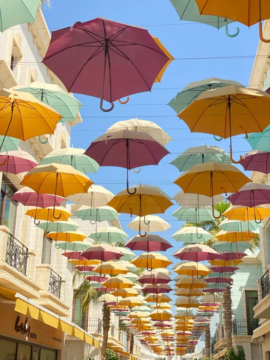 a street filled with lots of colorful umbrellas, unsplash, cyprus, shades of yellow, iridescent colours, looking upward