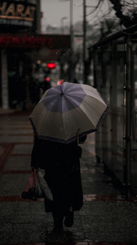 a person walking in the rain with an umbrella, unsplash photography, trending photo, low-light, color photo