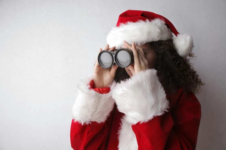 a girl in a santa suit looking through a pair of binoculars, a photo, by Emma Andijewska, cyber goggles, promo image, contain, plain