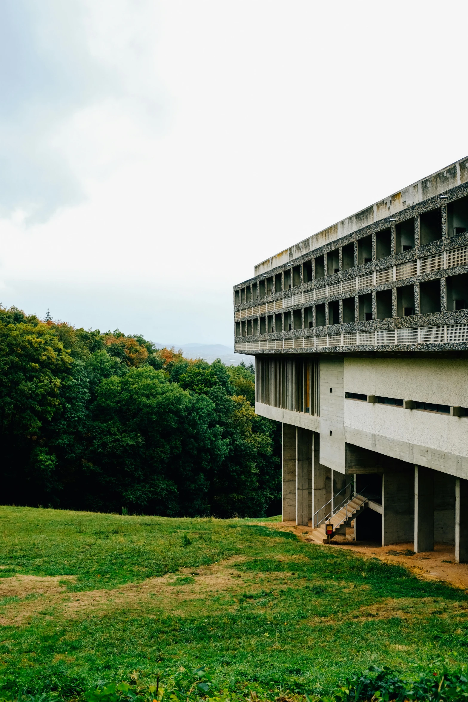 a large concrete building sitting on top of a lush green field, unsplash, brutalism, slovakia, balconies, in the hillside, college