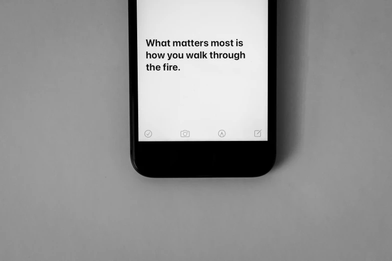 a cell phone with the text what matters most is how you walk through the fire, a black and white photo, trending on pexels, postminimalism, mobile learning app prototype, quotev, ffffound, front side