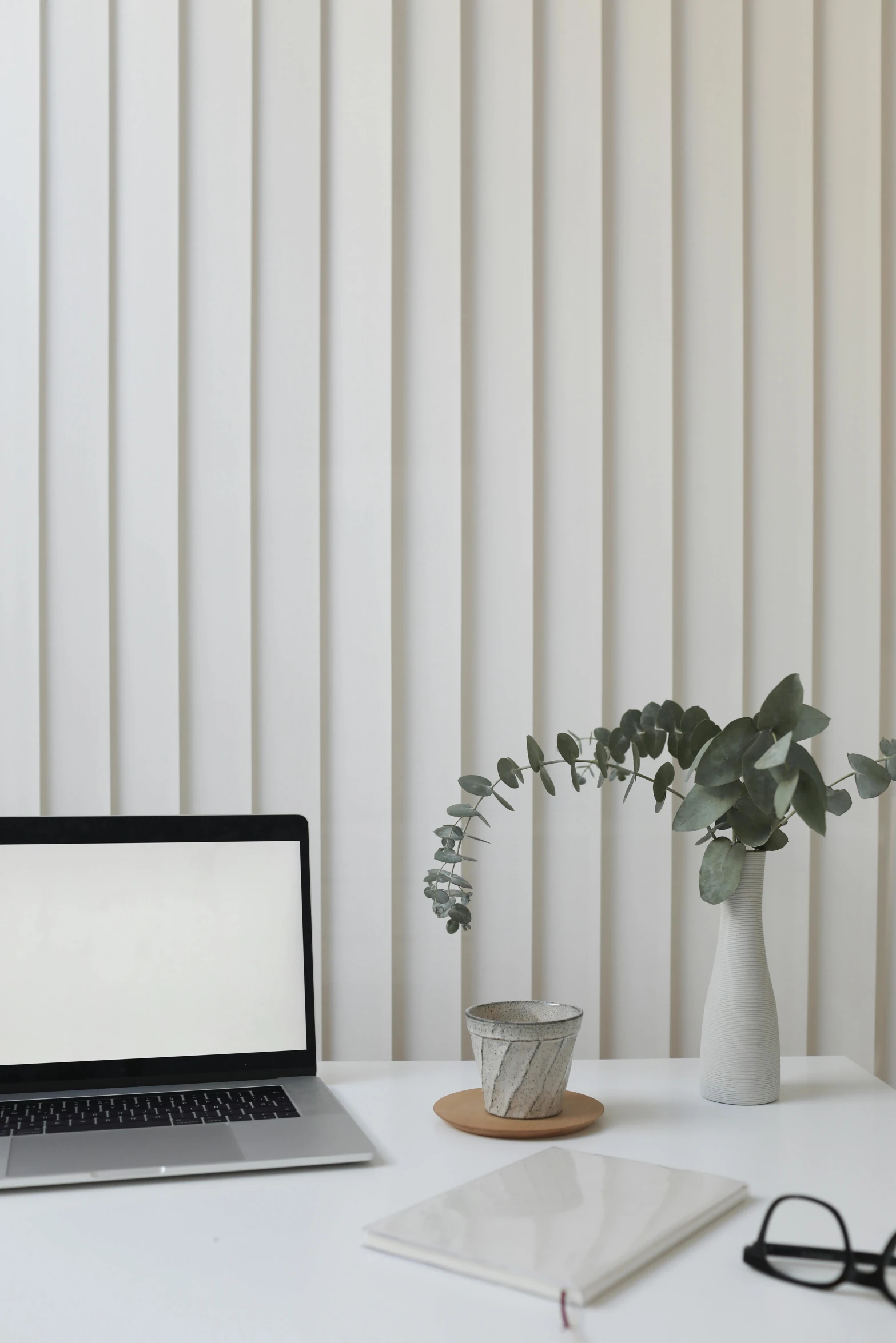 a laptop computer sitting on top of a white desk, trending on pexels, postminimalism, grey striped walls, eucalyptus, vertical lines, white vase