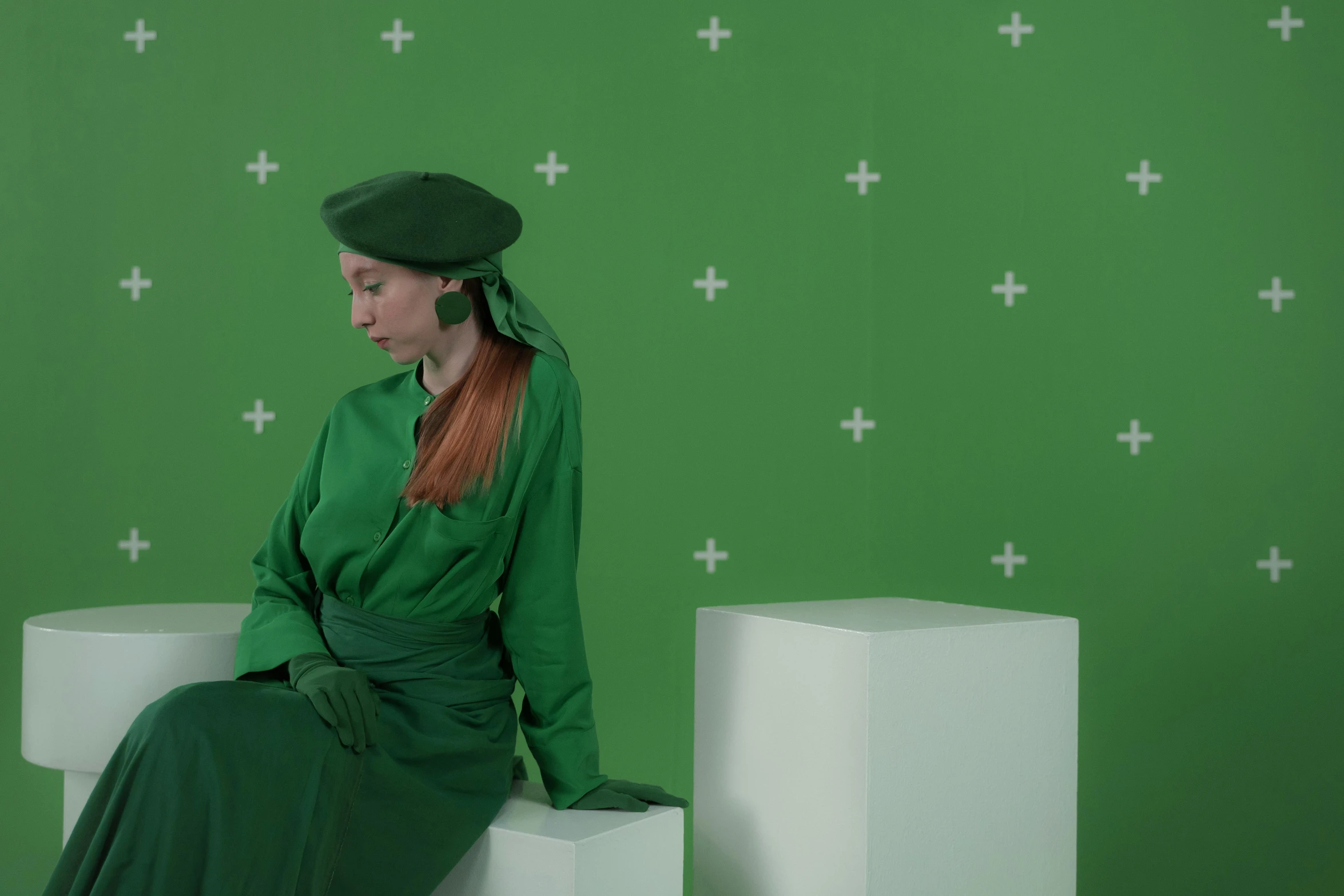 a woman in a green dress sitting on a white pedestal, inspired by Art Green, trending on pexels, conceptual art, wearing a beret, green screen, luminescent fabrics, still from l'estate