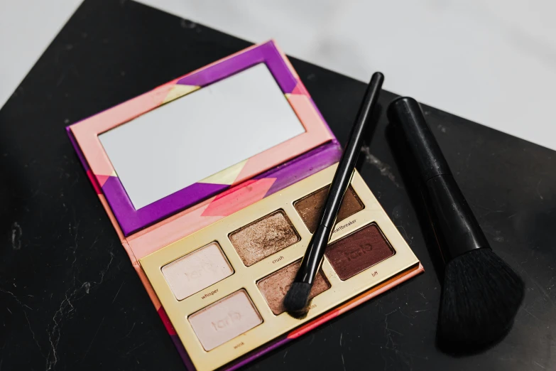 a makeup palette and brush sitting on a table, by Julia Pishtar, lit from behind, mascara, a brightly coloured, bronze