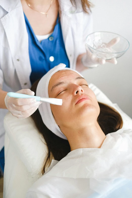 a woman getting a facial treatment in a beauty salon, by Adam Marczyński, shutterstock, coerent face and body, made of lab tissue, square, cysts
