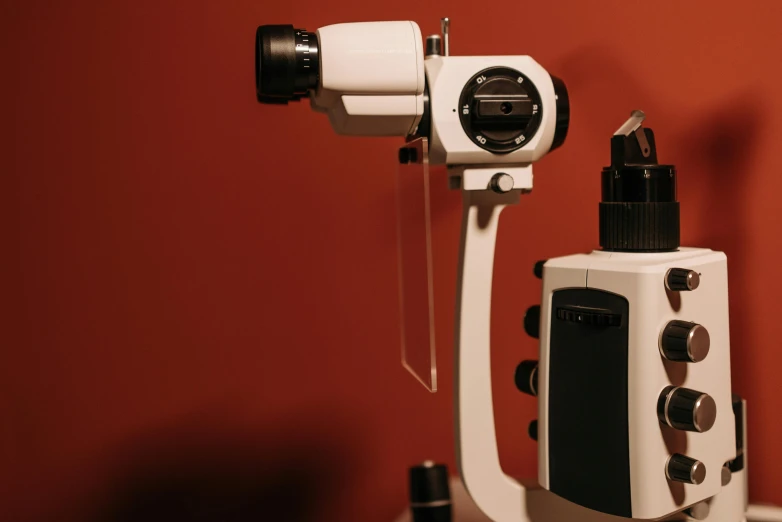 a camera sitting on top of a table next to a bottle, a microscopic photo, black spot over left eye, digital medical equipment, aesthetic shot, brown