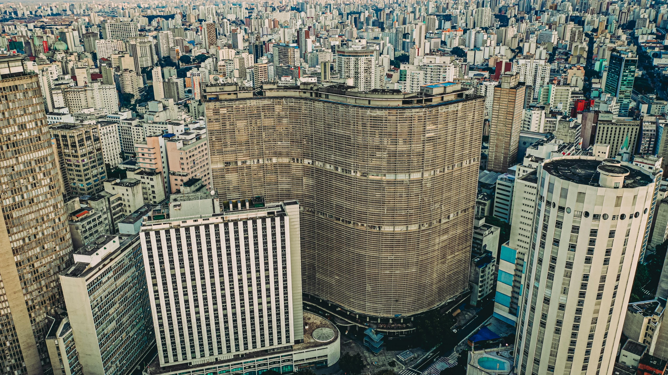 a view of a city from the top of a building, an album cover, inspired by Antônio Parreiras, pexels contest winner, brutalism, curvy build, brown, big poor building, brazil