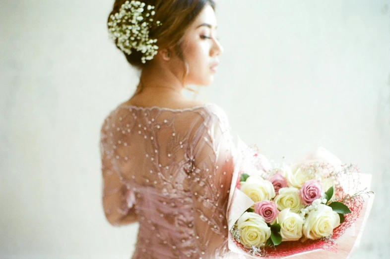 a woman in a pink dress holding a bouquet of flowers, inspired by Ruth Jên, tumblr, romanticism, bokeh intricate details, cindy avelino, exposed back, studio photo