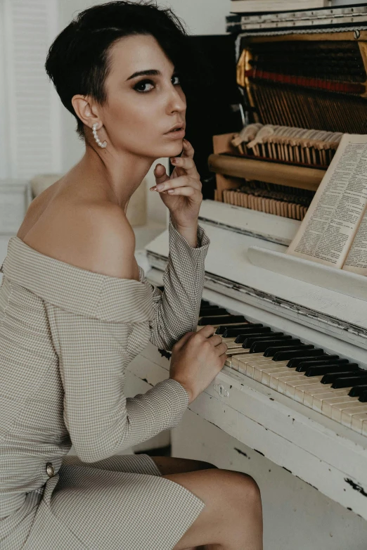 a woman sitting in front of a piano, inspired by Elsa Bleda, trending on pexels, baroque, morena baccarin, muted palette mostly white, attractive neck, low quality photo