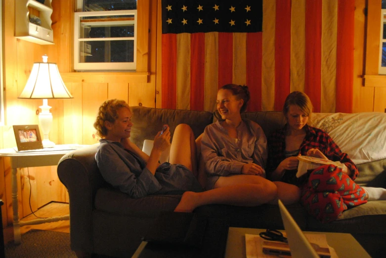 three women sitting on a couch in a living room, flickr, stars and stripes, cabin lights, sydney sweeney, college