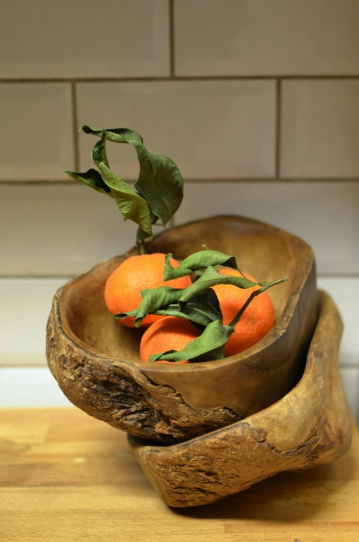 a wooden bowl filled with oranges on top of a counter, driftwood sculpture, greens), bespoke, petite