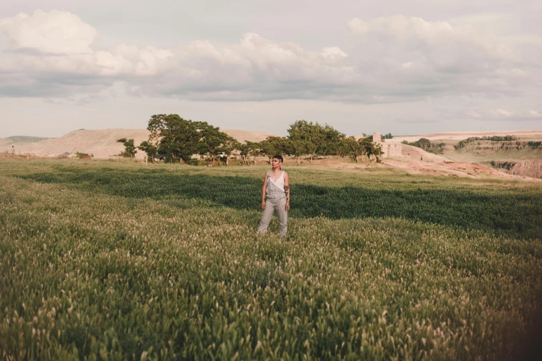 a woman standing in a field of tall grass, by Nina Hamnett, unsplash, renaissance, agrigento, wide view of a farm, sienna, man standing