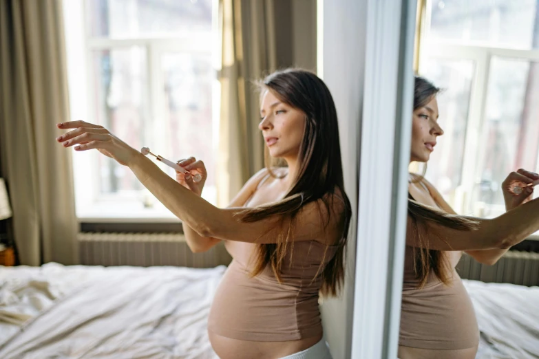 a woman standing in front of a mirror brushing her teeth, by Julian Hatton, pexels contest winner, happening, pregnant belly, sitting on edge of bed, avatar image, holding a syringe