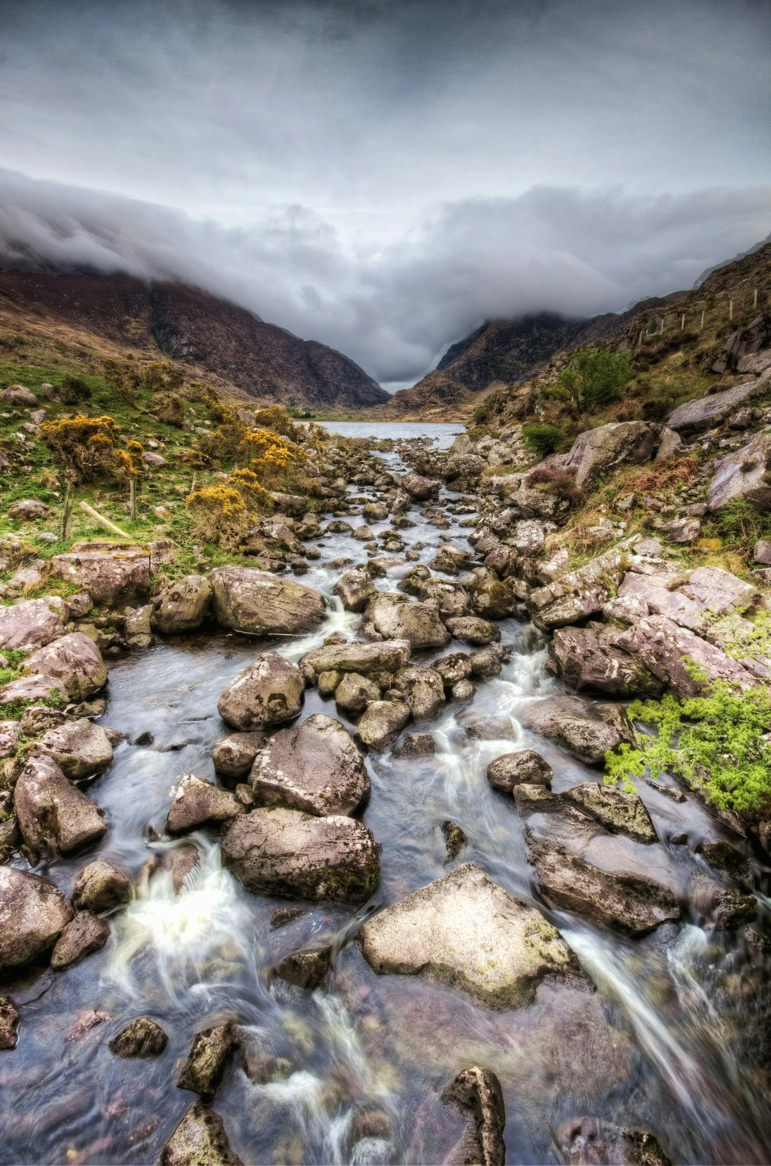 a river running through a lush green valley, by Bedwyr Williams, wet rocks, a lake between mountains, irish, phot