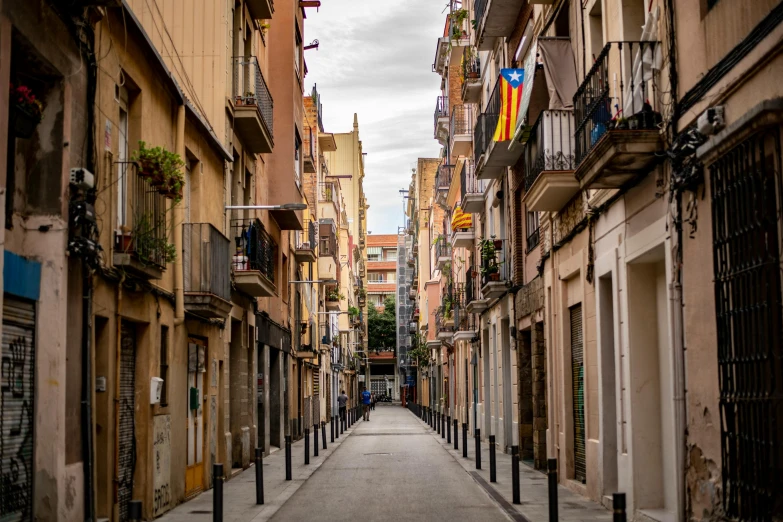 a narrow street lined with tall buildings and balconies, inspired by Modest Urgell, pexels contest winner, graffiti, square, spanish, a quaint, university