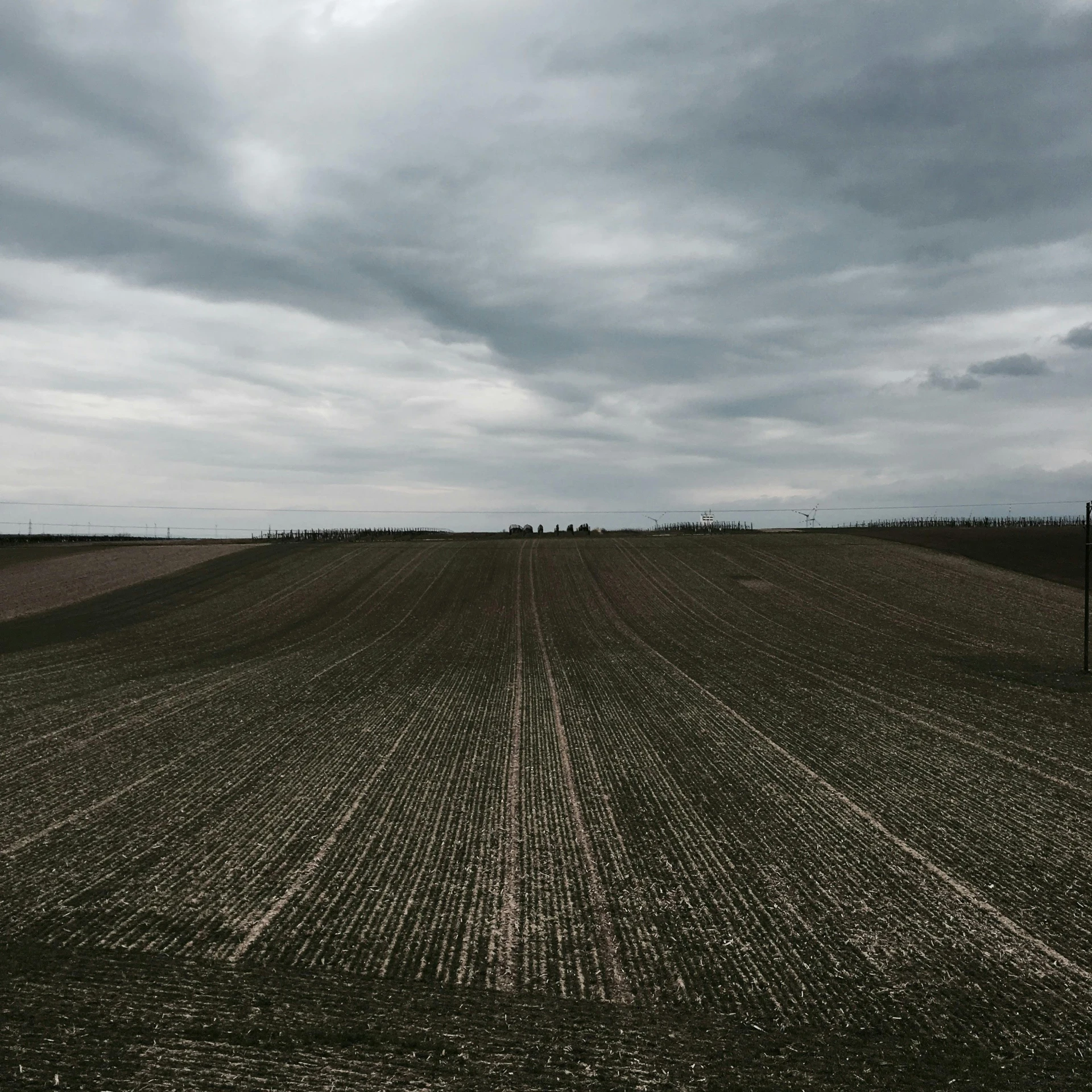 a plowed field under a cloudy sky, an album cover, inspired by Andreas Gursky, pexels contest winner, land art, gray skies, striped, dark gloomy, wide high angle view