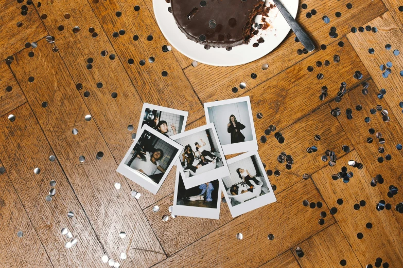 a chocolate cake sitting on top of a wooden table, a polaroid photo, by Lucia Peka, unsplash, happening, confetti, gal gadot china plate, group portraits, 1990's photo