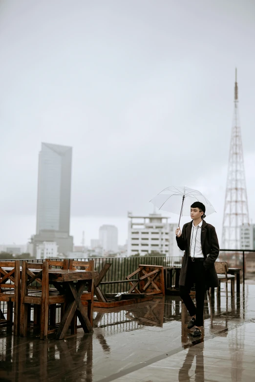 a man standing in the rain holding an umbrella, an album cover, inspired by Cheng Jiasui, pexels contest winner, sitting on a skyscraper rooftop, standing in a restaurant, ao dai, city morning