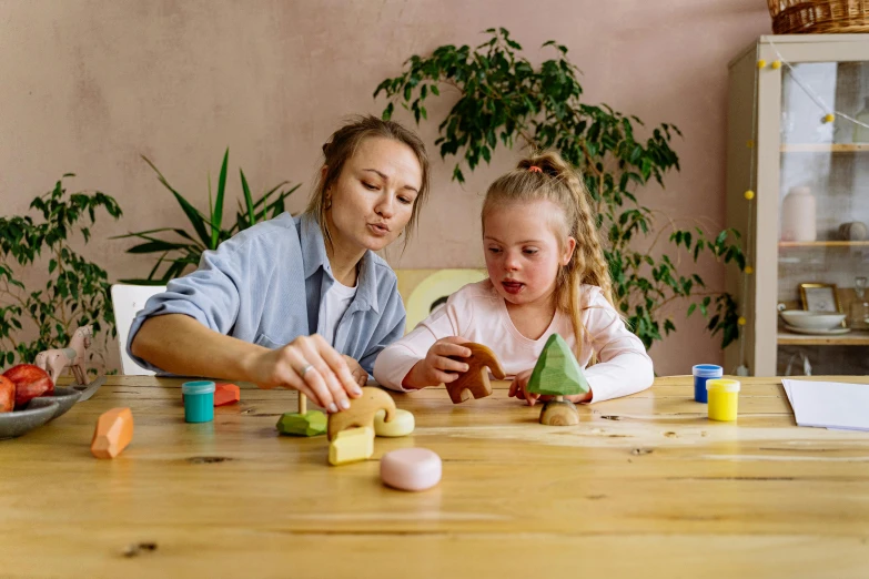 a woman and a little girl sitting at a table, pexels contest winner, kids toys, solid coloured shapes, surreautistic, a wooden