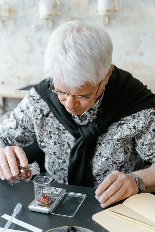 a woman sitting at a table with a glass of wine, process art, silver small glasses, carefully crafted, elder, manuka