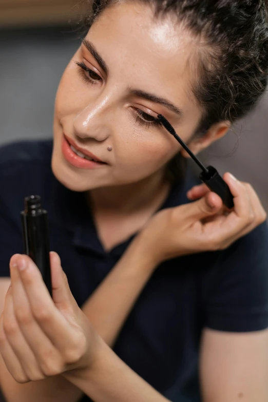 a woman putting on mascara in front of a mirror, pexels contest winner, promo image, profile image, girl with dark brown hair, thumbnail