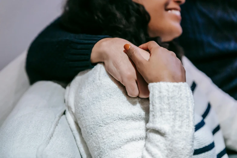 a woman sitting on top of a couch next to a man, trending on pexels, romanticism, hugging each other, black haired girl wearing hoodie, woman holding another woman, tiny details