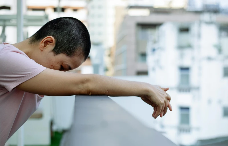 a man in a pink shirt leaning on a railing, a picture, inspired by Ren Hang, pexels contest winner, happening, crying and reaching with her arm, on rooftop, boy has short black hair, sao paulo