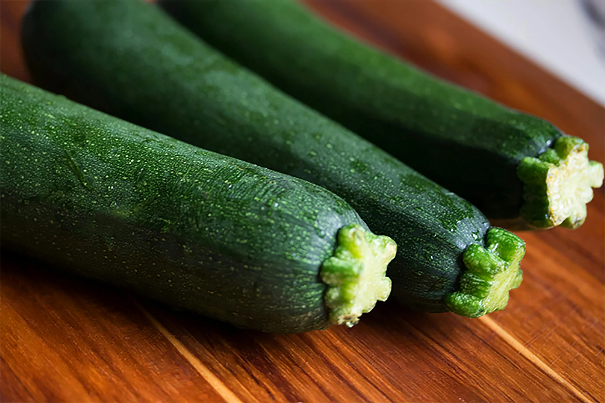 a couple of zucchini sitting on top of a wooden cutting board, 6 pack, square, shot with sony alpha, medium closeup