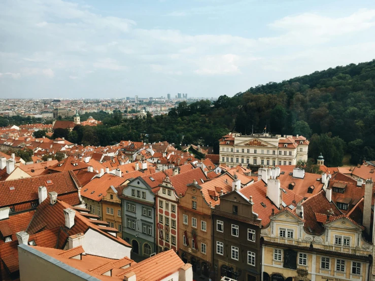 a view of a city from the top of a building, by Emma Andijewska, pexels contest winner, art nouveau, orange roof, slide show, square, hills in the background