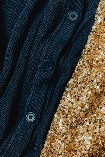 a close up of a shirt with buttons on it, an album cover, by Julia Pishtar, trending on pexels, renaissance, colors with gold and dark blue, sequins, textured base ; product photos, gold and black blu
