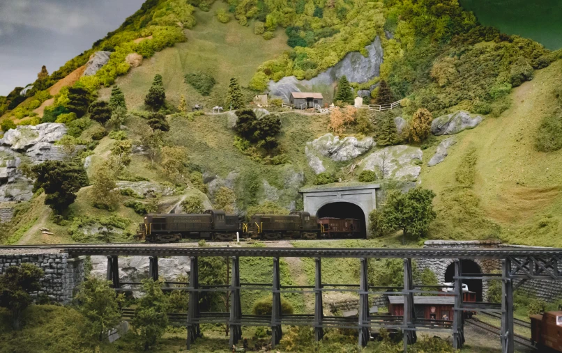 a model train is coming out of a tunnel, a matte painting, by Dan Frazier, unsplash, figuration libre, large diorama, with lots of vegetation, looking over west virginia, museum photo