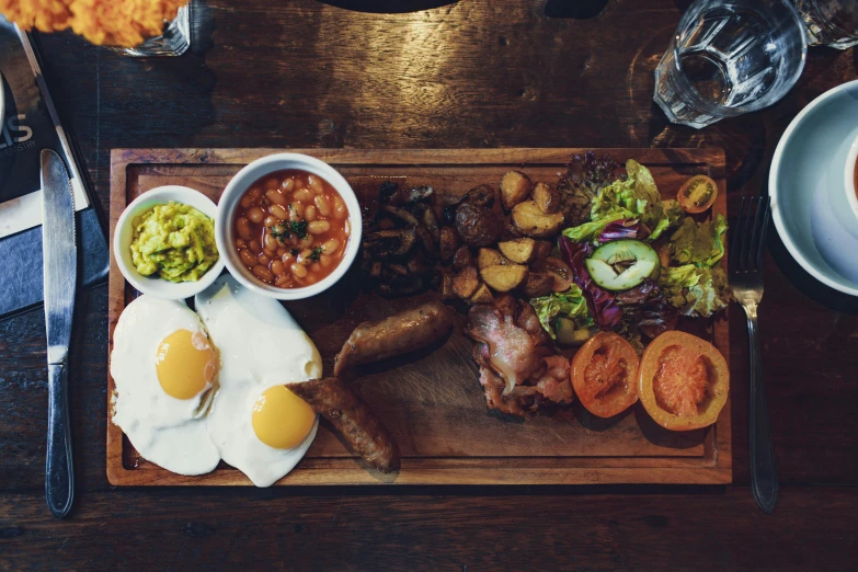 a wooden cutting board topped with food next to a cup of coffee, by Lee Loughridge, pub, eggs, breakfast buffet, 🦩🪐🐞👩🏻🦳