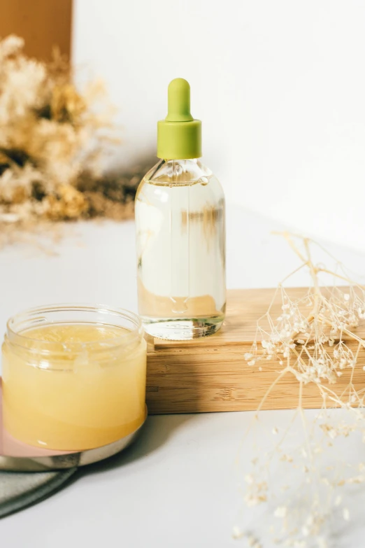 a bottle of liquid sitting next to a jar of liquid, unsplash, with textured hair and skin, chamomile, made of bamboo, jelly glow